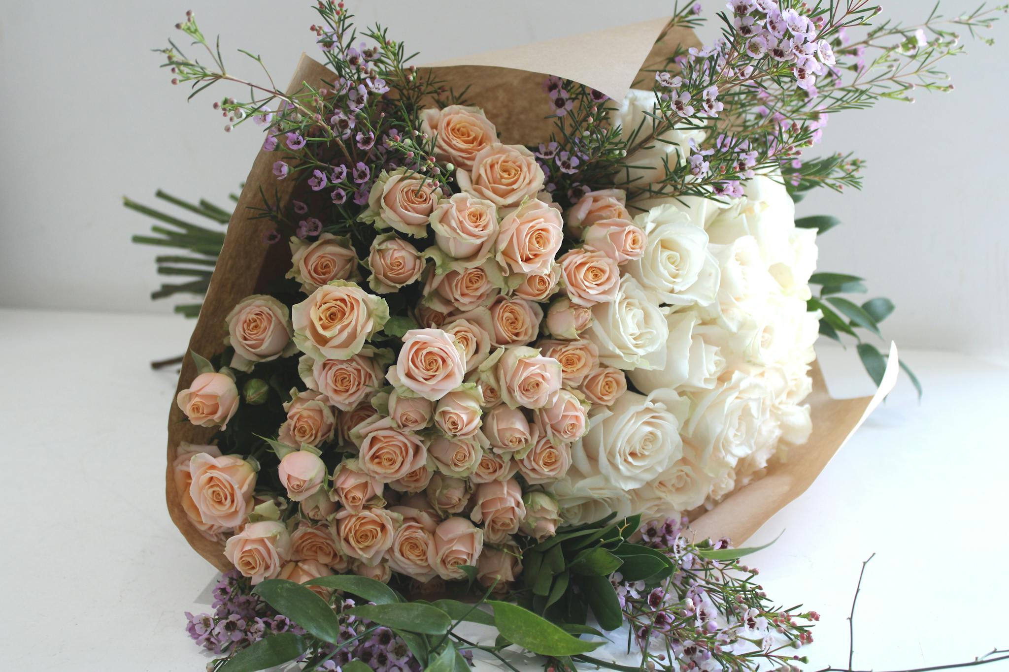 white and peach roses with wax flower bouquet